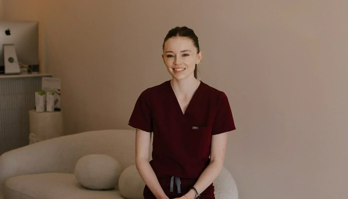 Nurse Maddy in maroon scrubs seated in the CQ Aesthetics treatment room